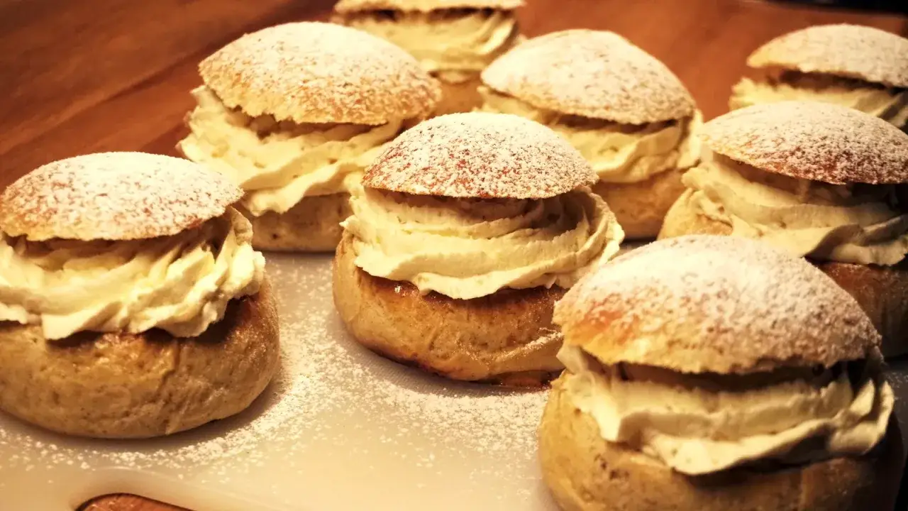 En samling gammaldags semlor, generöst fyllda med vispgrädde och pudrade med florsocker.