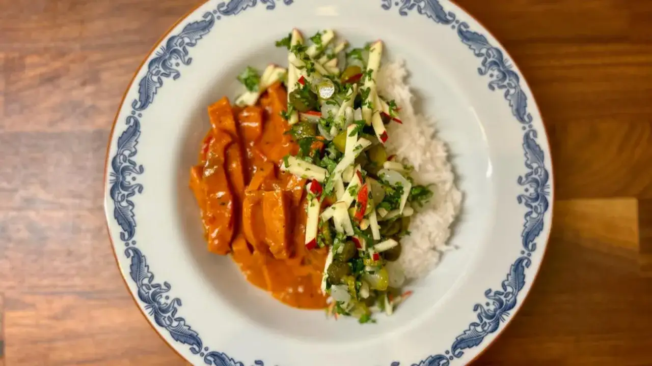 En tallrik med kr&auml;mig korv stroganoff, ris och en fr&auml;sch &auml;ppel- och gurksallad. Ett perfekt recept f&ouml;r godaste korv stroganoff!