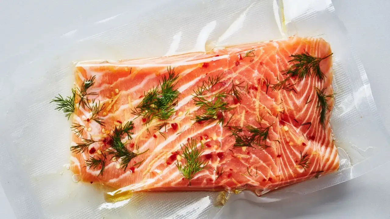 En bit lax f&ouml;r sous vide-tillagning, kryddad med dill och chili, ligger i en vakuump&aring;se.