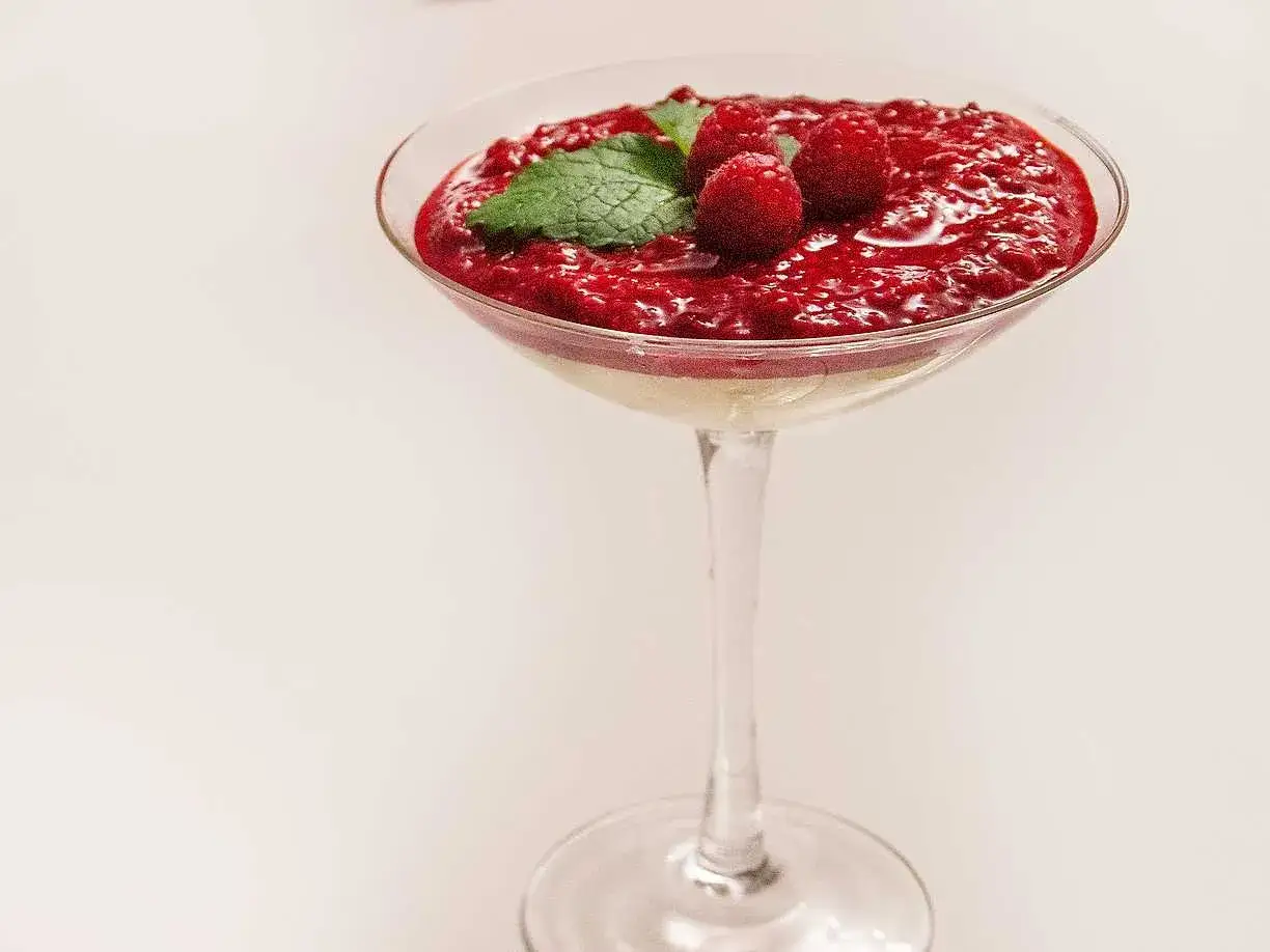 En elegant fryst cheesecake i ett glas, toppad med hallonsås, färska hallon och mynta. En perfekt sommardessert.