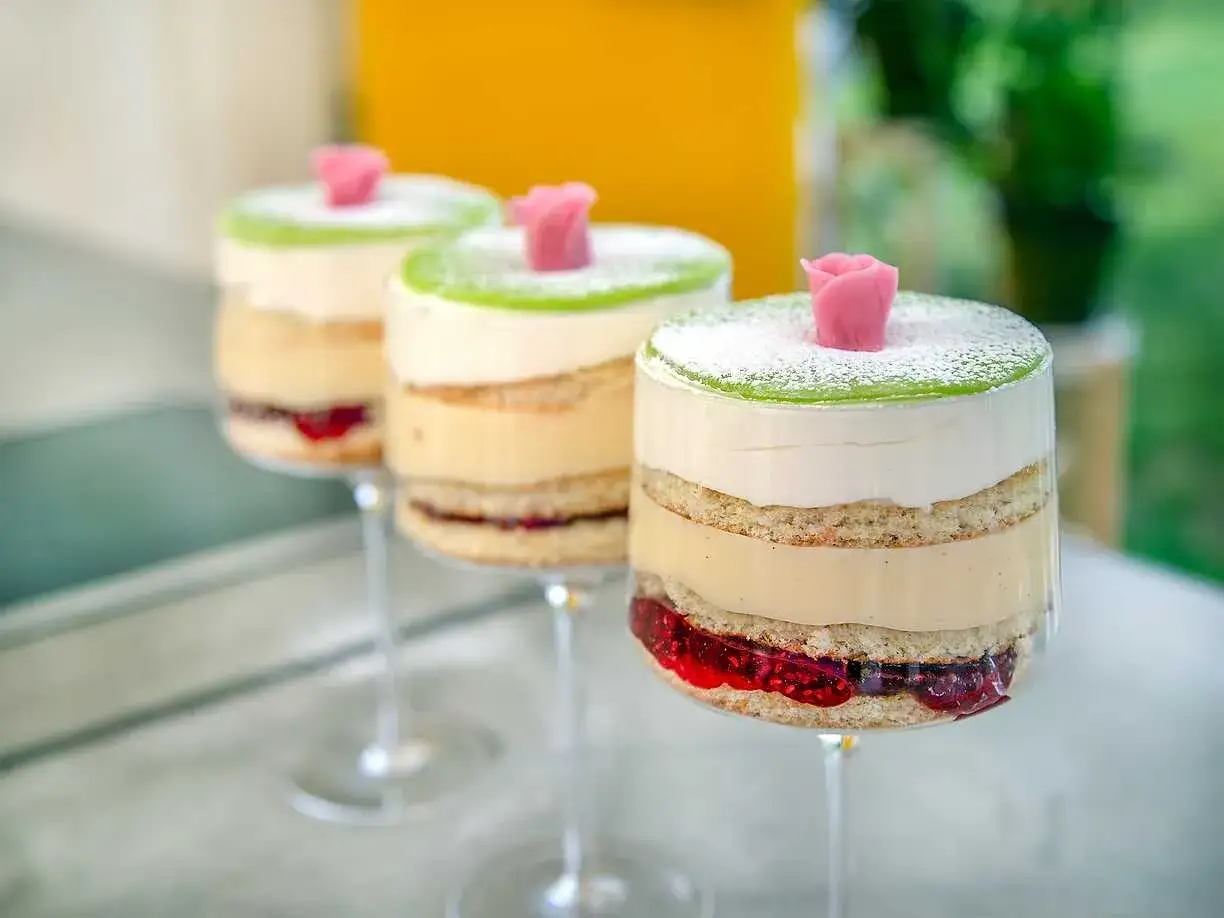 Tre vackra prinsesst&aring;rtor i glas, med lager av sockerkaka, gr&auml;dde, vaniljkr&auml;m och hallonsylt, toppade med gr&ouml;n marsipan och en rosa ros.