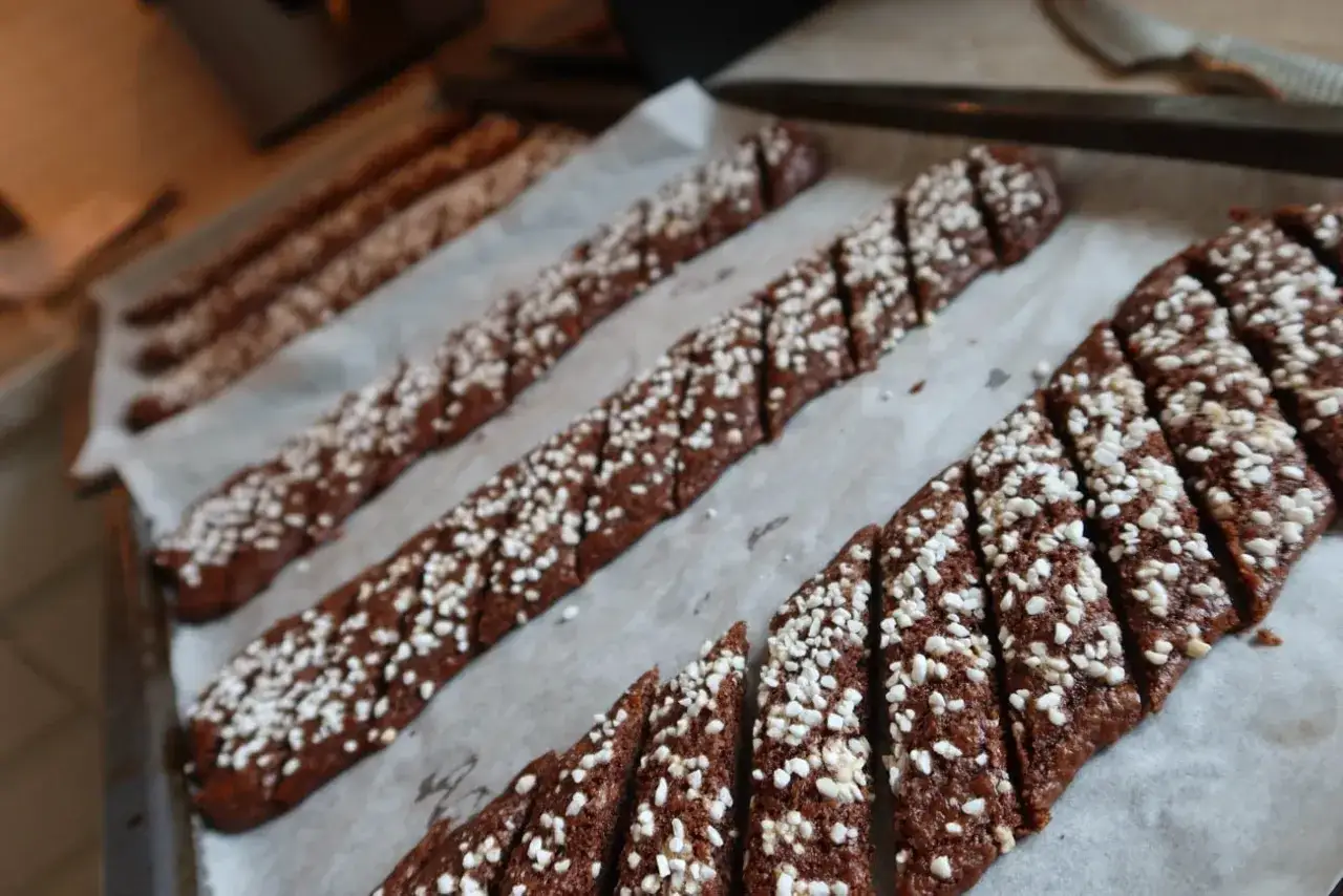 Chokladsnittar recept: Mörka, sockerströsslade kakor på bakplåtspapper, redo att gräddas.