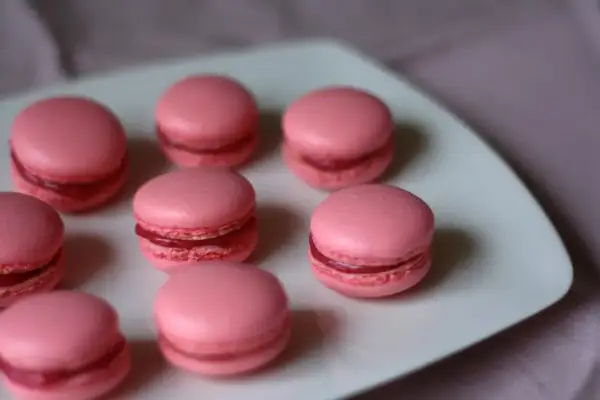 Rosa macarons med fyllning på en vit tallrik. Perfekt för ett macarons recept.