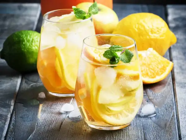 Två glas med uppfriskande vit sangria cava fyllda med frukt och is. Citroner, apelsiner och mynta ger en härlig sommarkänsla.