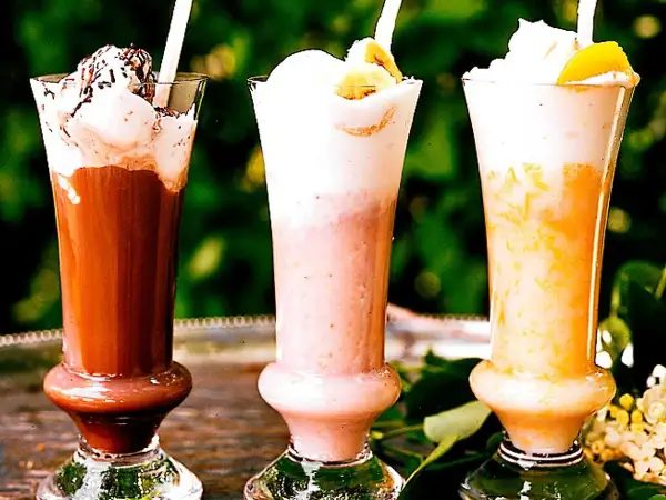 Tre läckra milkshakes i glas: choklad, jordgubb och aprikos. Perfekt för ett somrigt milkshake recept!