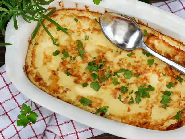 En gyllene omelett i ugn, toppad med färsk persilja och en sked redo att servera. Perfekt för en mysig frukost eller lätt lunch.