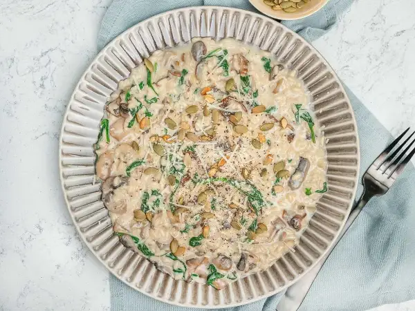Krämig risotto svamp med spenat och pumpafrön, toppad med parmesan och svartpeppar. En härlig rätt som värmer själen.