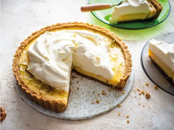 En krämig key lime pie med fluffig grädde, en bit serverad på en grön tallrik.