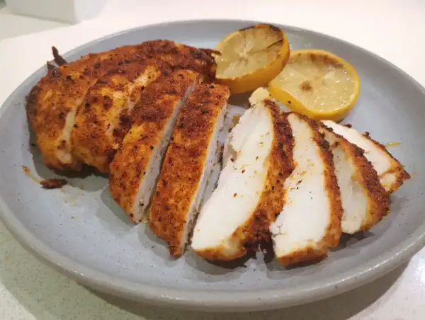 Saftig kyckling i airfryer, skivad och serverad med grillade citronklyftor. Perfekt för en snabb och god middag.