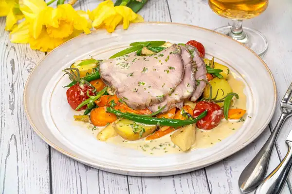 Skinkstek med rotfrukter och grönskaker, perfekt skuren för att visa rätt skinkstek temperatur. En härlig vårmåltid.